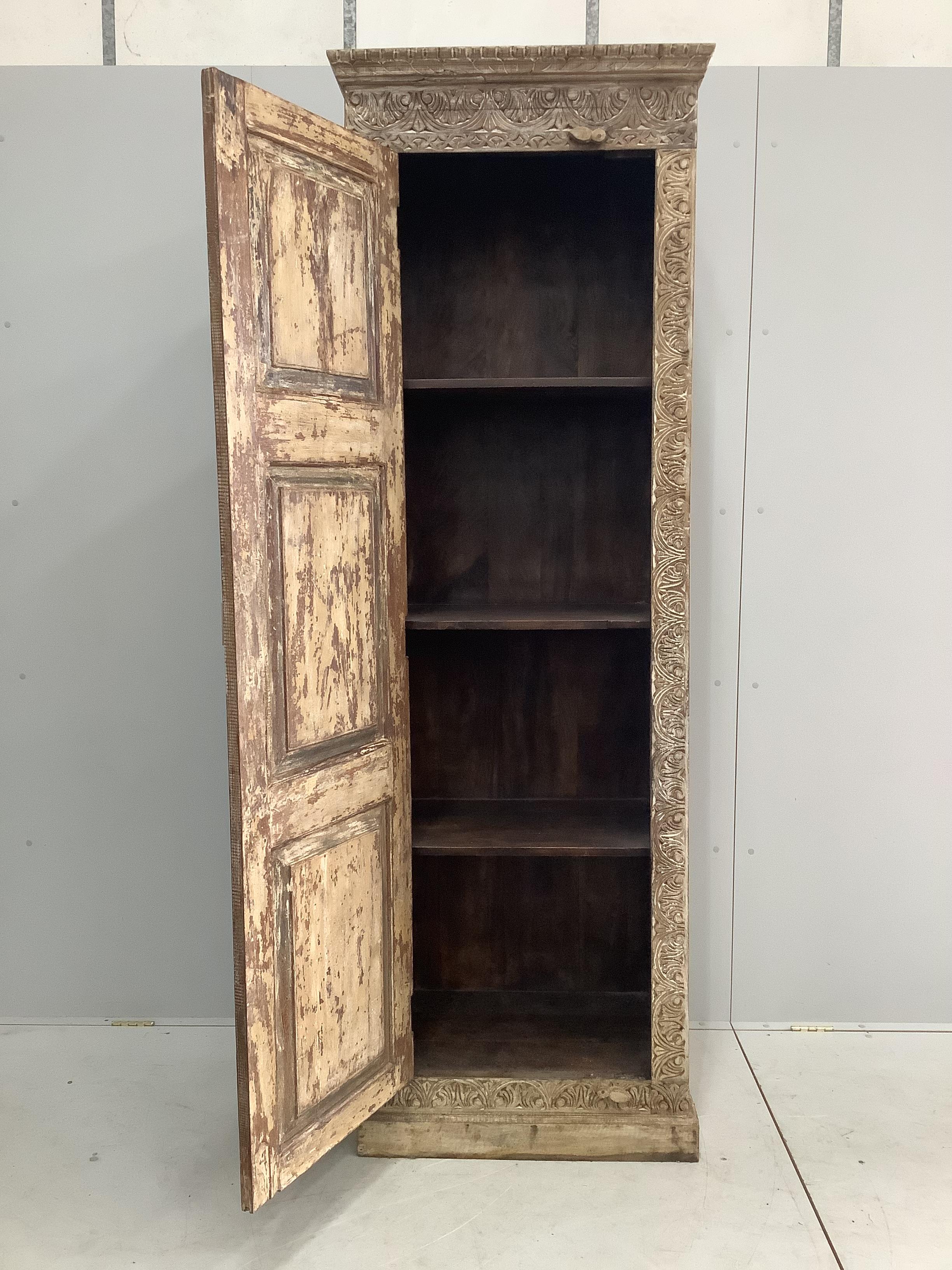 An Indian carved hardwood tall side cabinet, width 72cm, depth 48cm, height 218cm